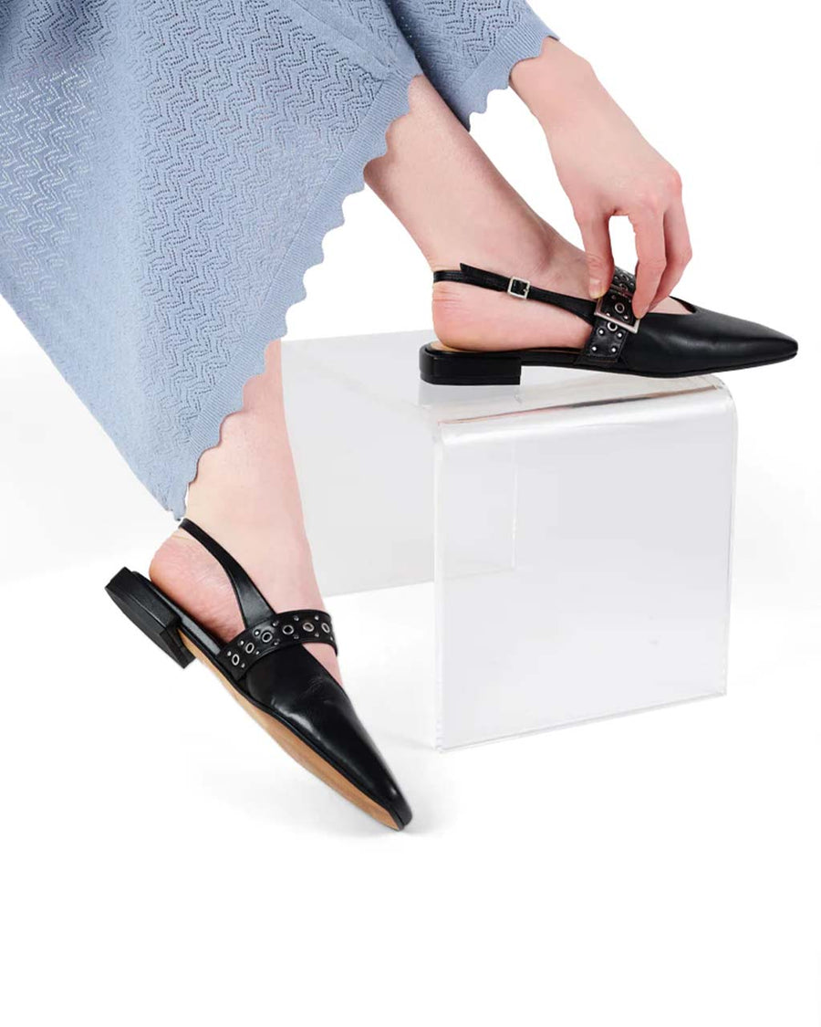 model wearing black slingback flat with large grommet buckle and square toe