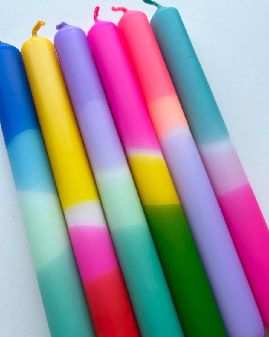 up close of set of six colorful layered tapered candles