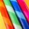 up close of set of 4 diagonally striped taper candles: red/orange, mint/clover green, light blue/royal blue and red/hot pink