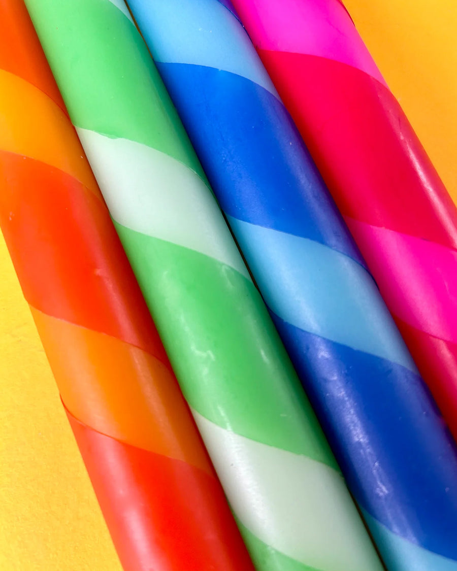 up close of set of 4 diagonally striped taper candles: red/orange, mint/clover green, light blue/royal blue and red/hot pink