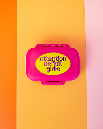 hot pink pill case with yellow 'attention deficit girlie across the front