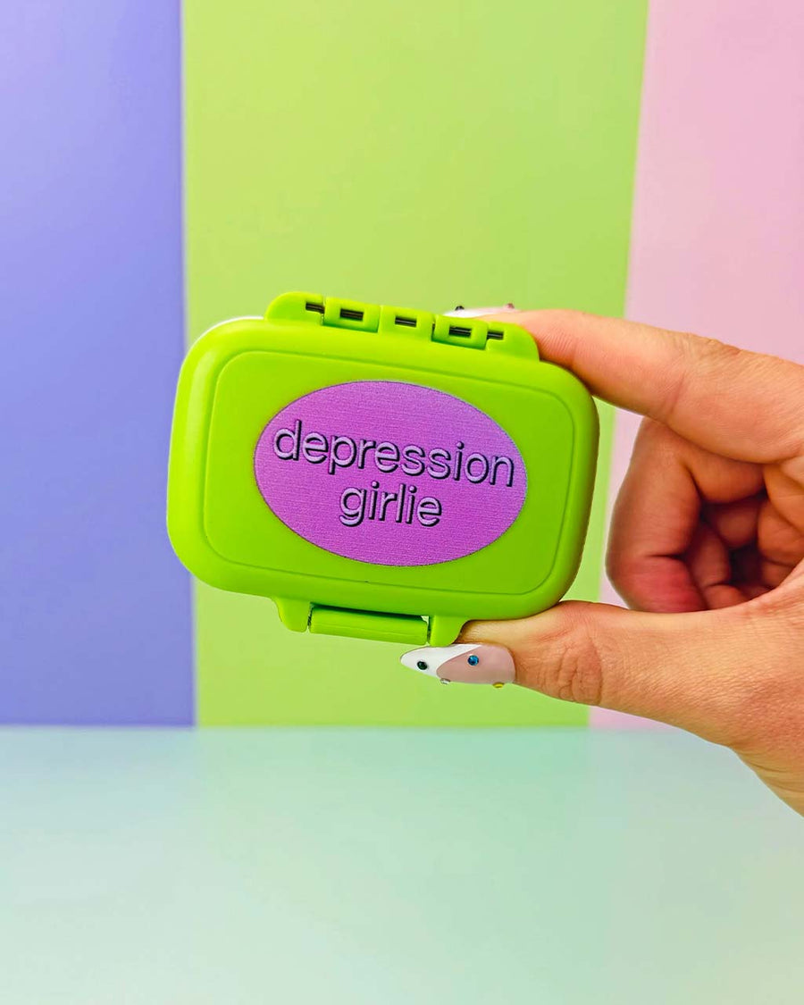 lime green pill case with purple 'depression girlie' across the front