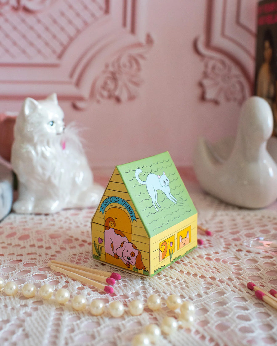 side view of colorful dog house shaped match box with pink tipped matches