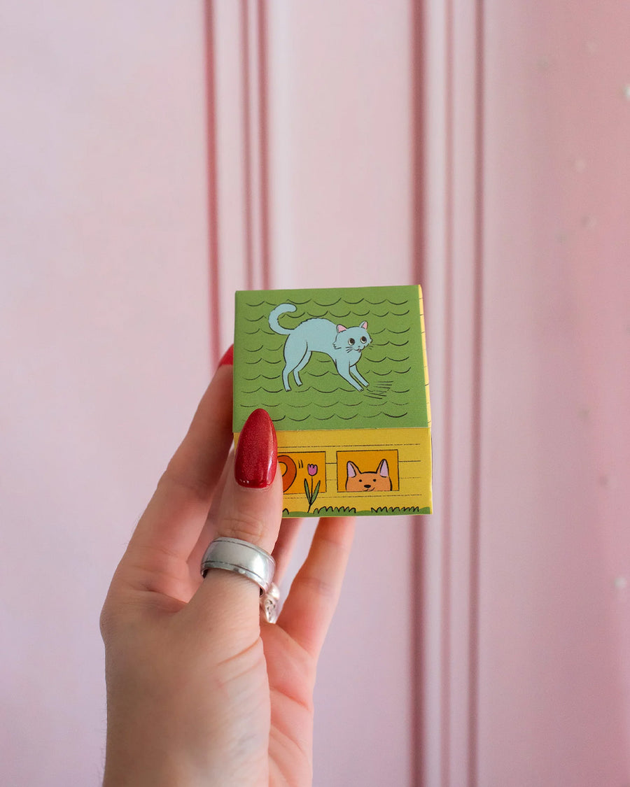 model holding colorful dog house shaped match box with pink tipped matches