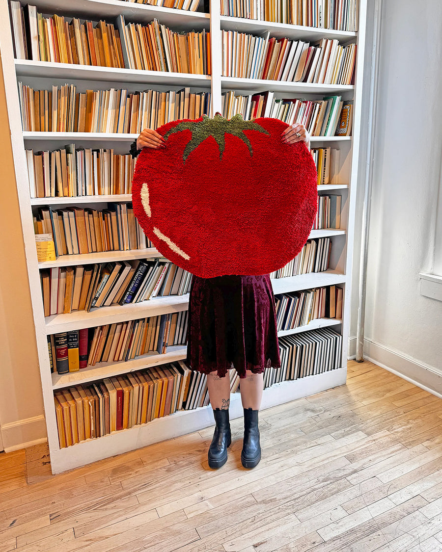 model holding large red beefsteak tomato throw rug