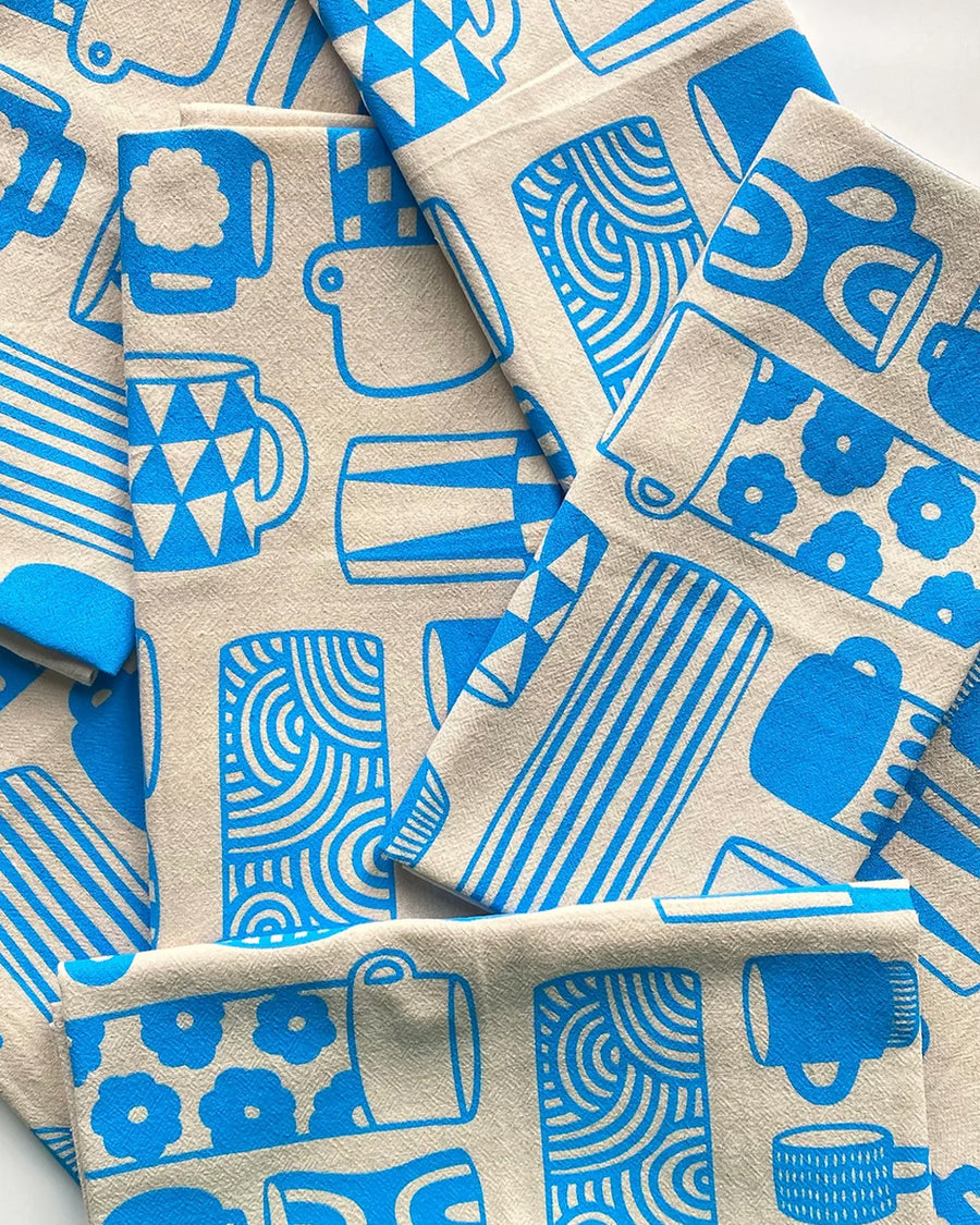 folded blue 'mug collection' print tea towel