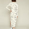 back view of model wearing cream midi dress with long sleeves, side slit, and all over navy 'doodle' print