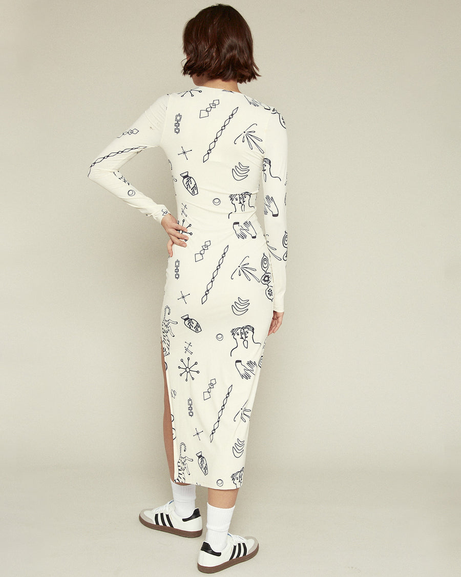 back view of model wearing cream midi dress with long sleeves, side slit, and all over navy 'doodle' print