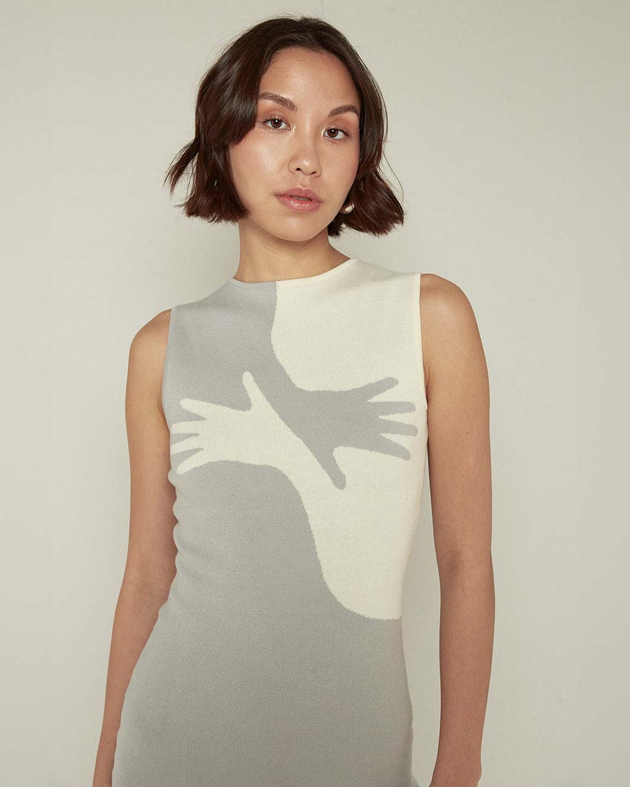 up close of model wearing grey and white mini dress with abstract criss crossing hands