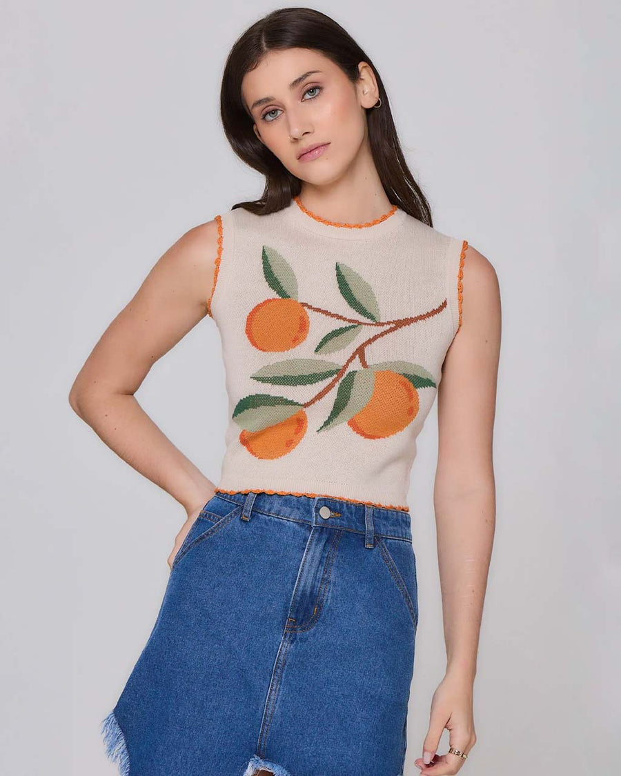 model wearing cream knitted vest with orange on a branch graphic and orange scalloped trim