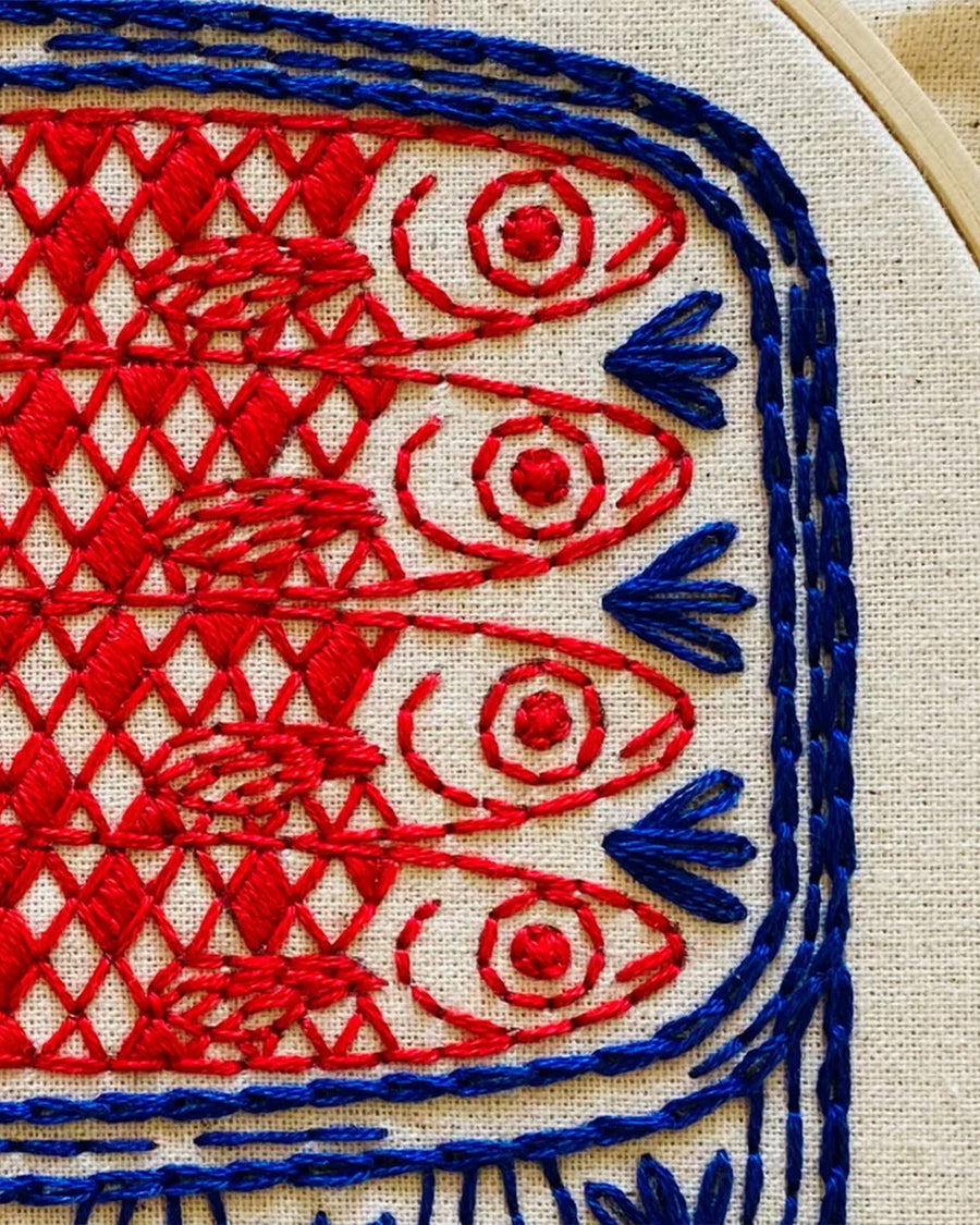 up close of red and blue tin sardine embroidery kit