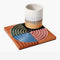 set of 4 terracotta coasters with colorful ribbed detail with cup on it