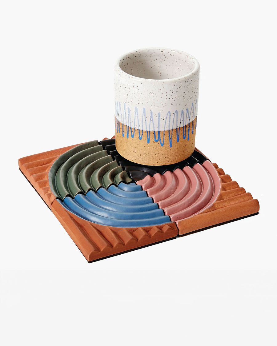 set of 4 terracotta coasters with colorful ribbed detail with cup on it