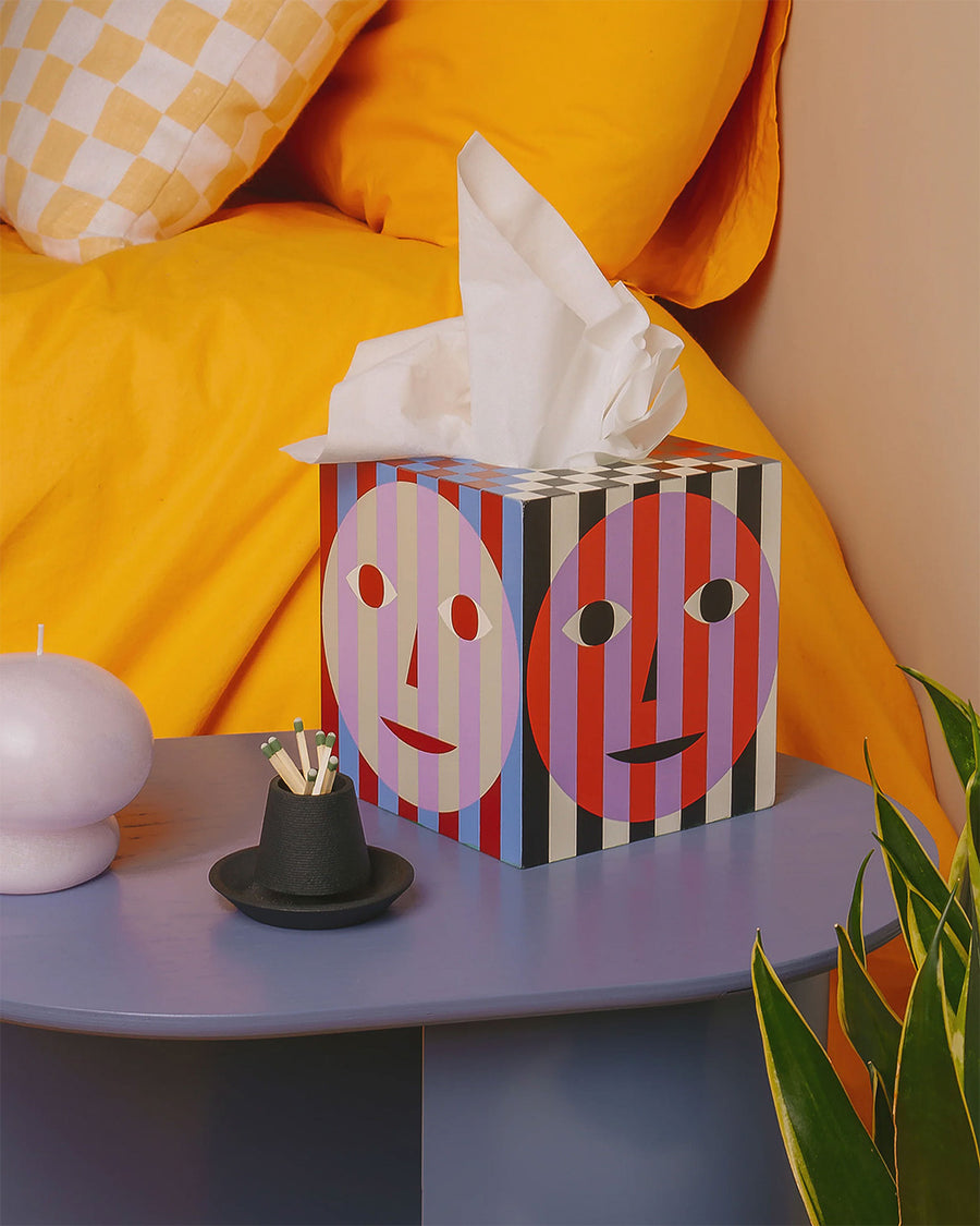 striped tissue box cover with colorful faces on a table