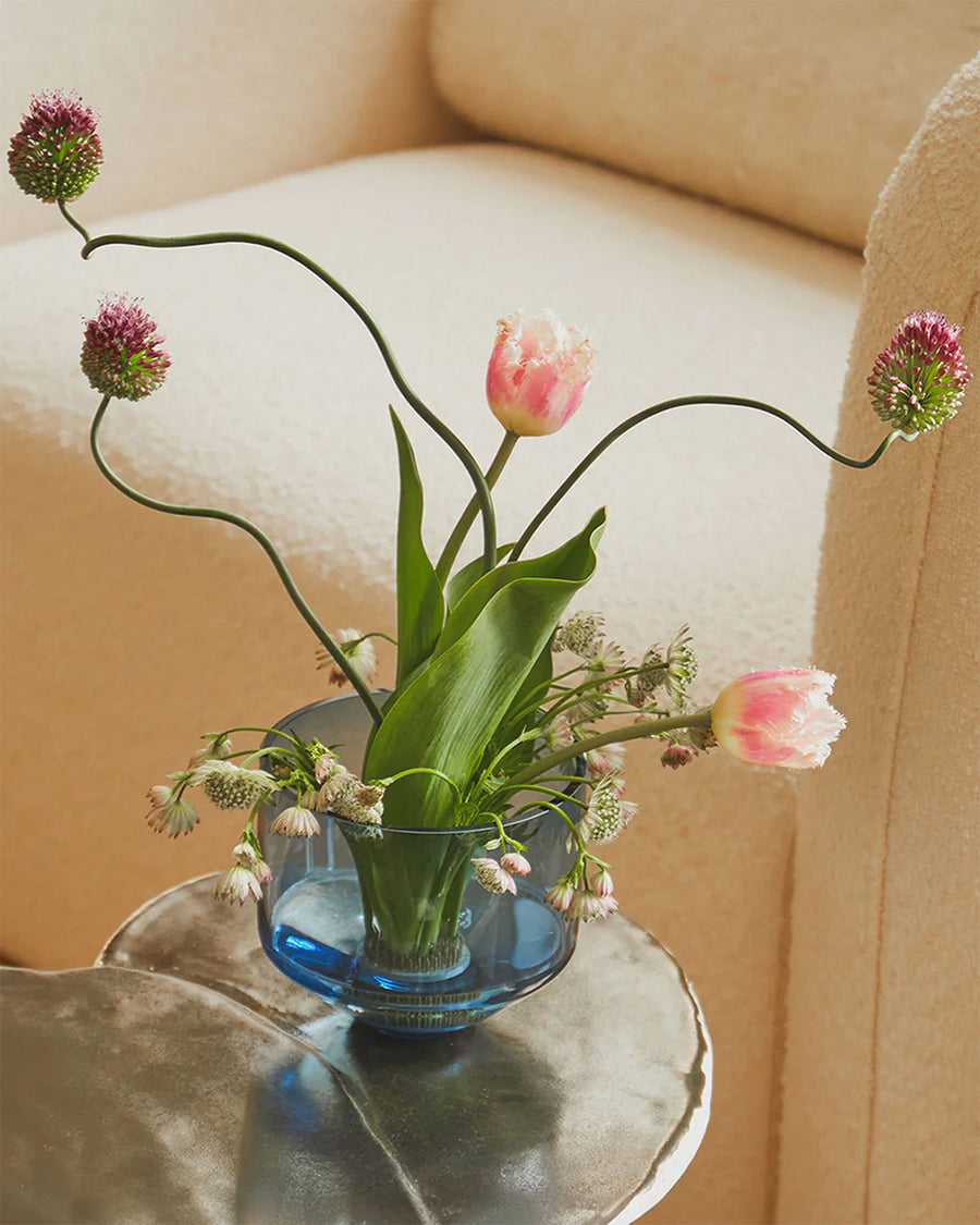 blue cylinder shaped vase with plant inside with flowers inside on a table