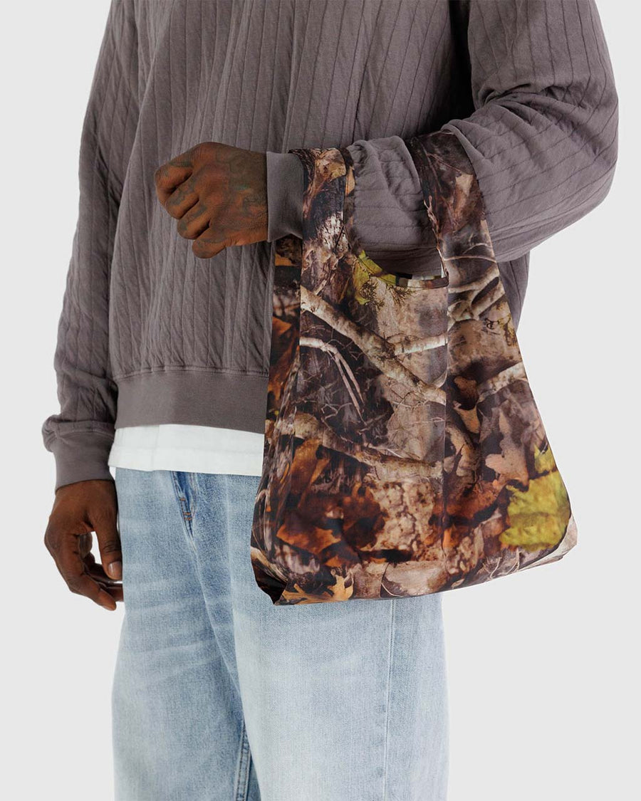 model holding baby baggu with life-like outdoor print with branches and leaves