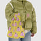 model holding yellow small baggu with snoopy in a bubblegum pink puffer coat and hat