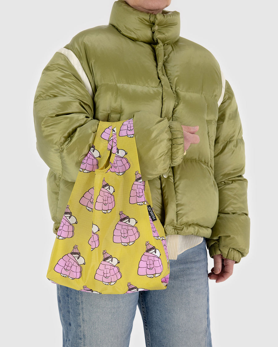 model holding yellow small baggu with snoopy in a bubblegum pink puffer coat and hat