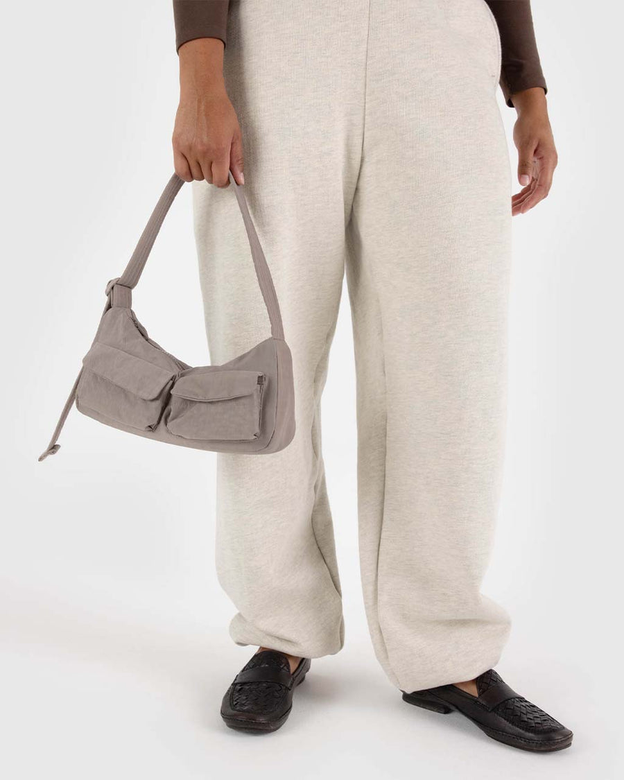 model holding taupe cargo shoulder bag with two front patch pockets in the front