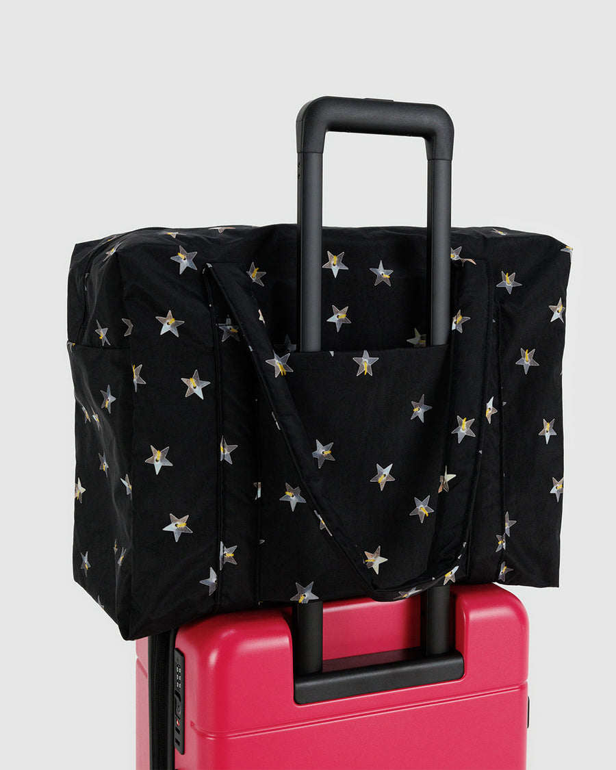 black baggu cloud carry on bag with silver metallic star print on a suitcase