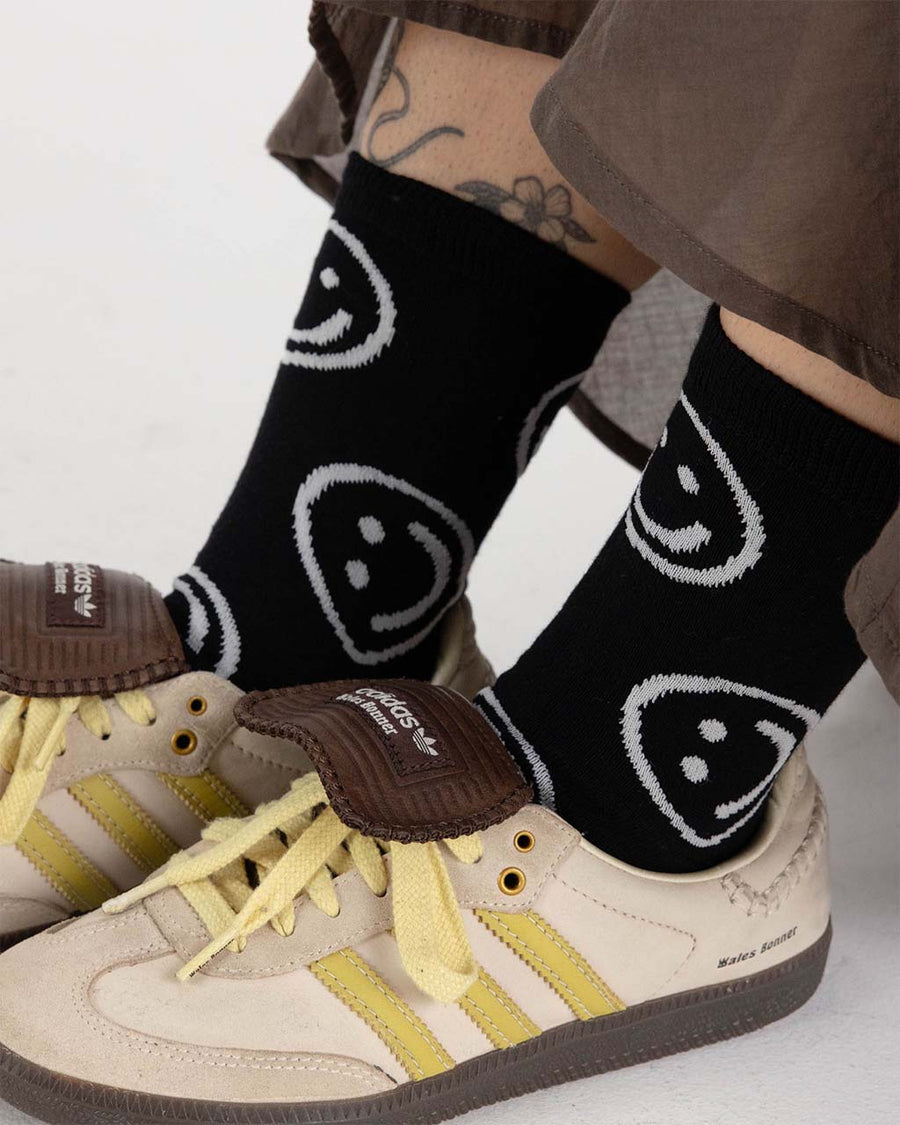 model wearing black crew socks with white smiley face print