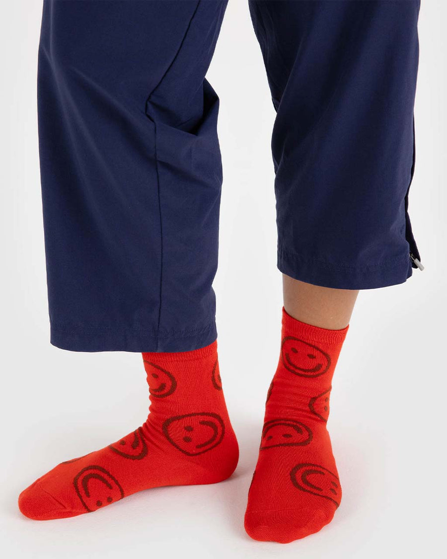 model wearing red crew socks with all over brown smiley face print