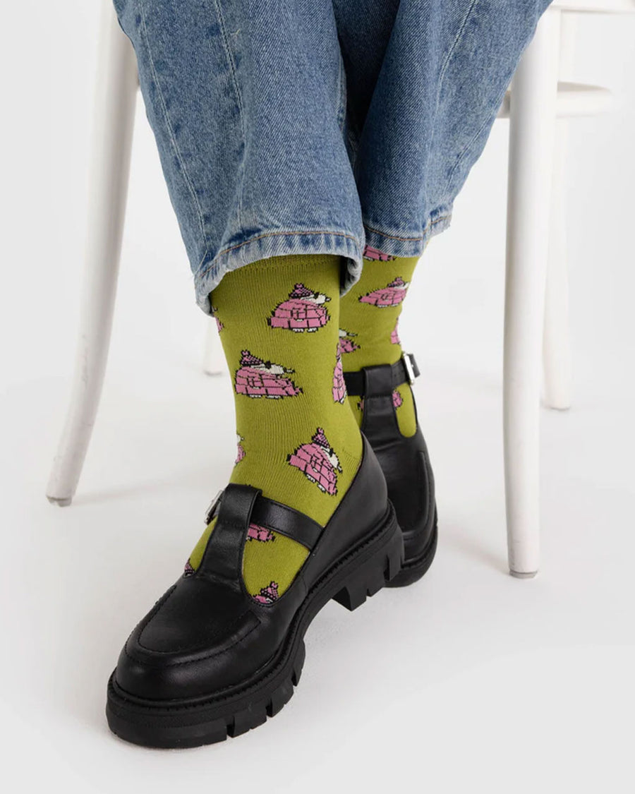 model wearing avocado green crew socks with snoopy in a pink puffer coat