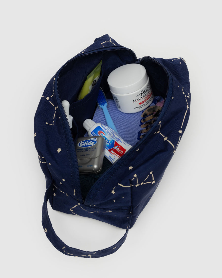 navy dopp kit with white constellation print with items inside