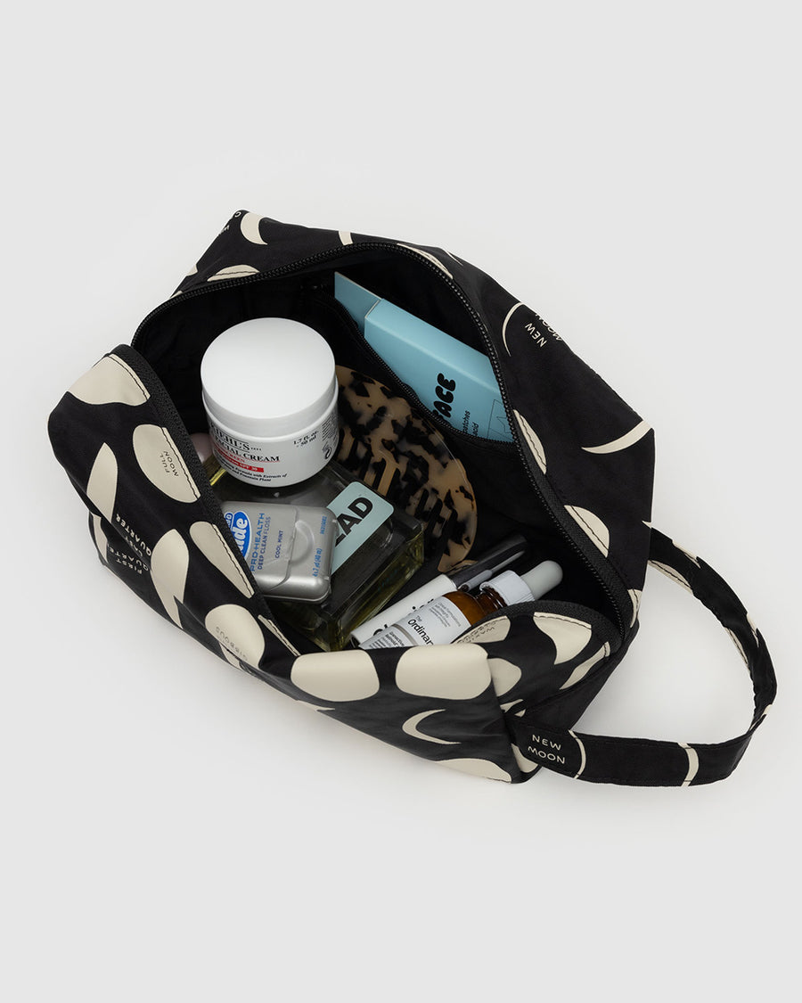 black dopp kit with cream moon phase print with items inside