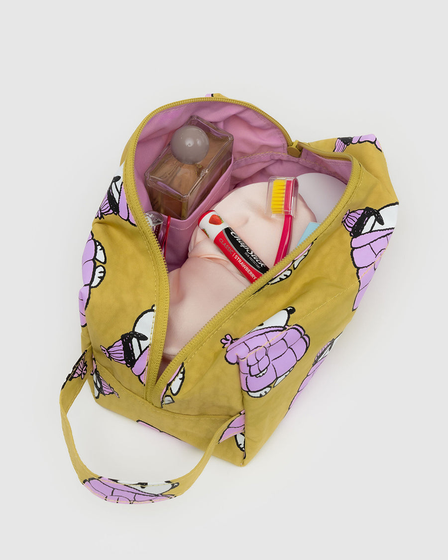 mustard yellow dopp kit with snoopy in a pink puffer coat and hat with items inside