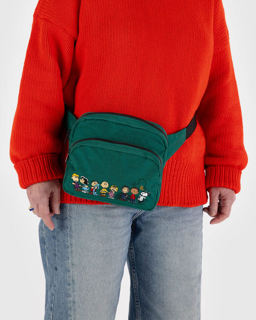 model wearing green fanny pack with the peanuts characters across the front