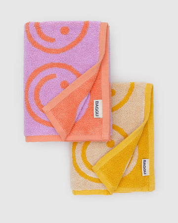 set of two hand towels with lilac smiley print and marigold smiley