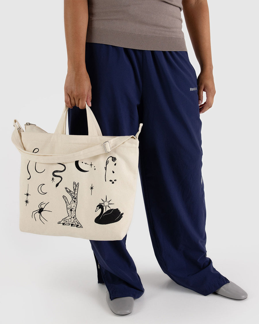 model holding cream horiztonal zip bag with black embroidered ballet icons design