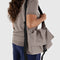 model carrying taupe large messenger bag with black strap and closure 