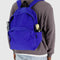 model wearing large bright blue nylon backpack with two front zipper compartments and drink holder on the side