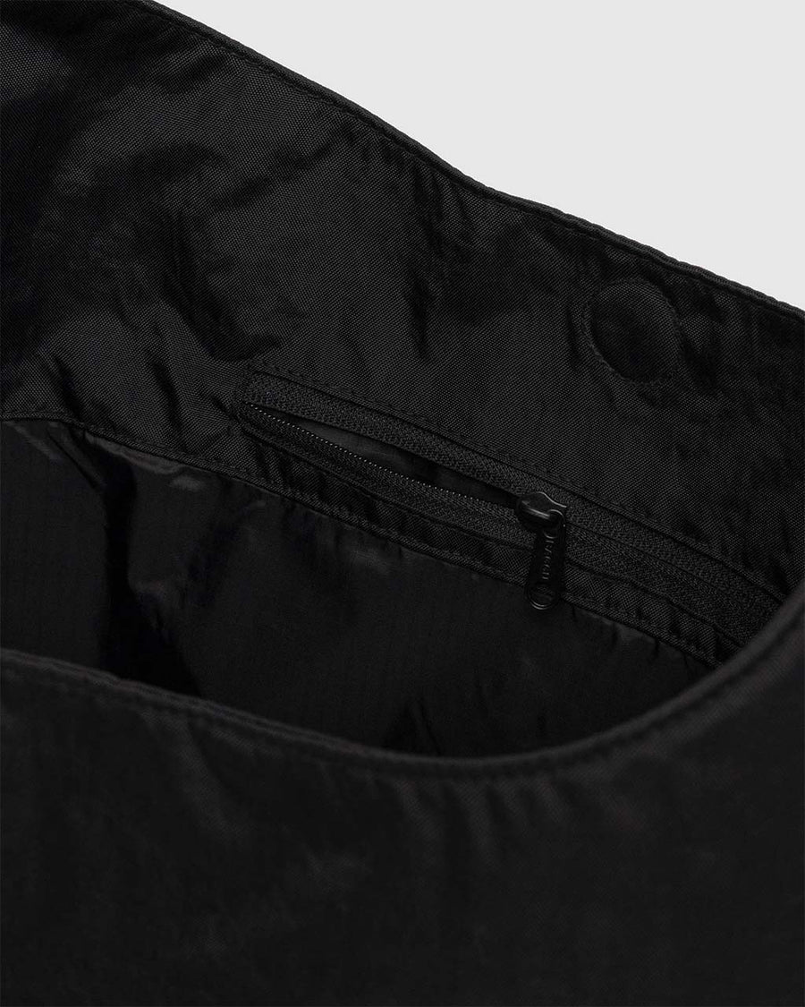 interior zipper pocket of large black nylon sling bag with adjustable strap