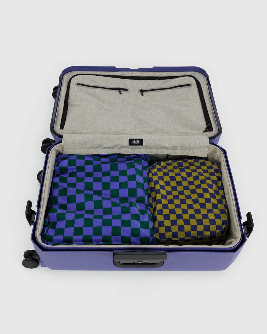 set of two large packing cubes: olive/navy checker and bright blue/dark green checker inside a suitcase