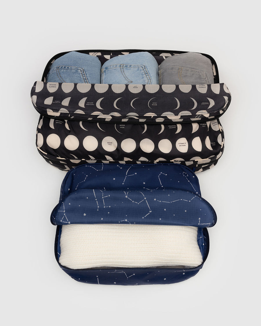 set of 2 large packing cubes: navy with white constellations and black with moon phases with items inside