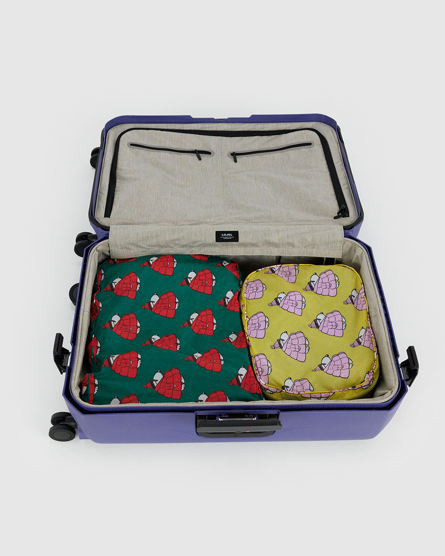 set of two large packing cubes: yellow with snoopy wearing pink puffer coat, and green with snoopy wearing a red puffer coat in a suitcase