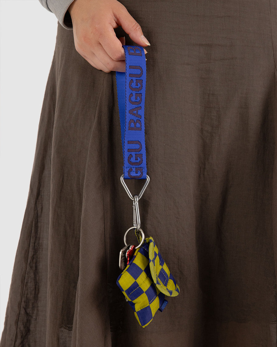 model holding cobalt keychain with dark blue 'baggu' font attached to a purse