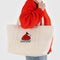 modle carrying medium heavyweight canvas tote with snoopy in a red puffer jacket and embroidered snoopy'