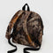 back view of realistic forest print nylon backpack with large zipper compartment, front zipper pocket, and side drink holder