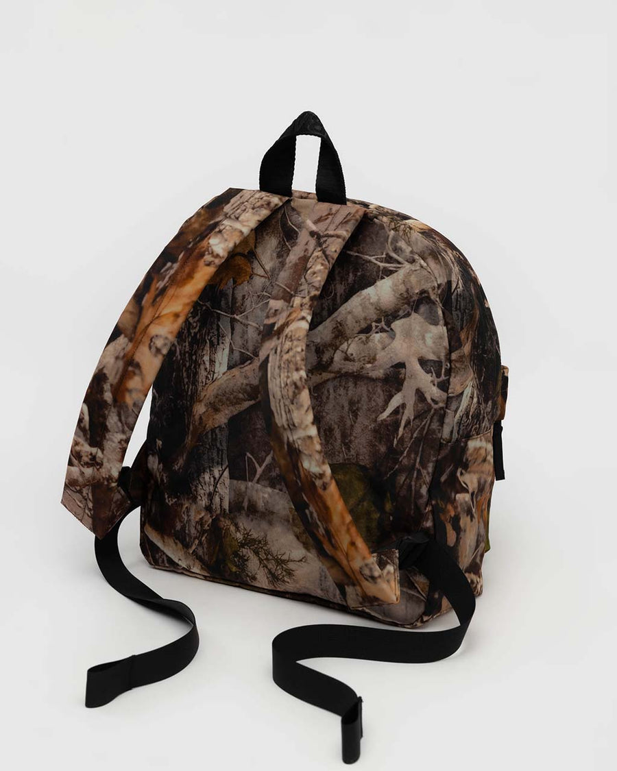 back view of realistic forest print nylon backpack with large zipper compartment, front zipper pocket, and side drink holder