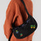 model wearing black and colorful cross stitch medium crescent bag