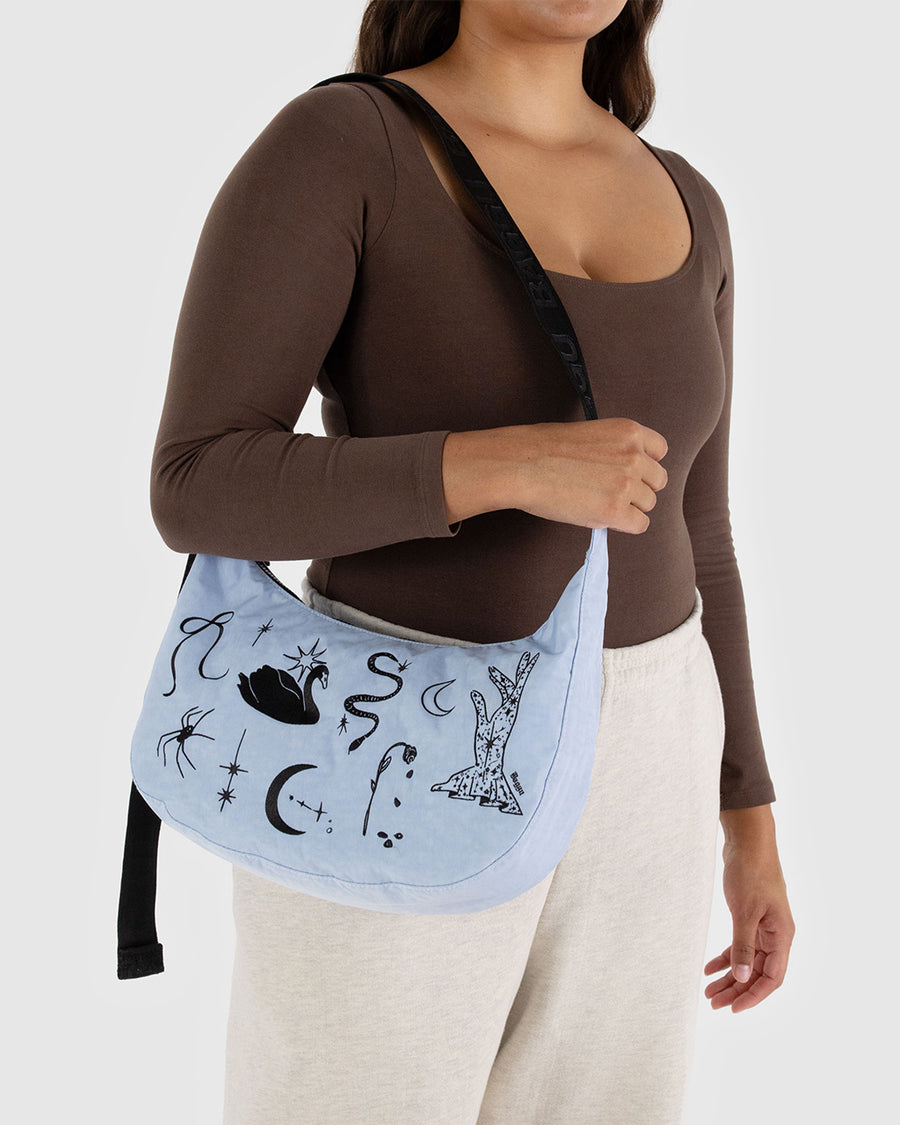 model carrying light blue medium crescent bag with black embroidered ballet icons 