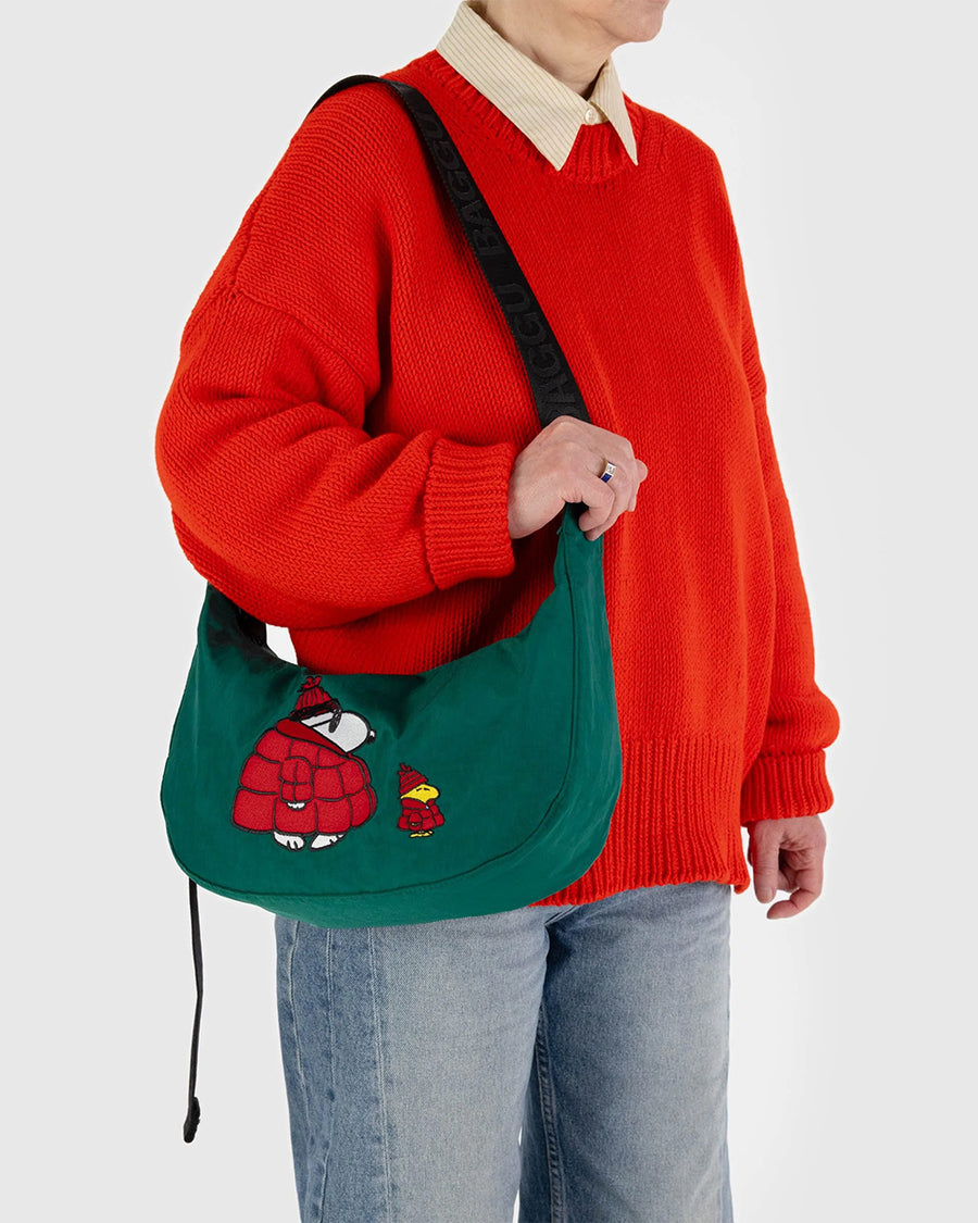 model carrying dark green medium crescent bag with snoopy and woodstock in a red puffer coat and hat