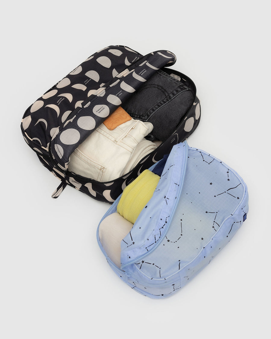 set of 2 packing cubes: light blue constellation, and black with cream moon phases with items inside