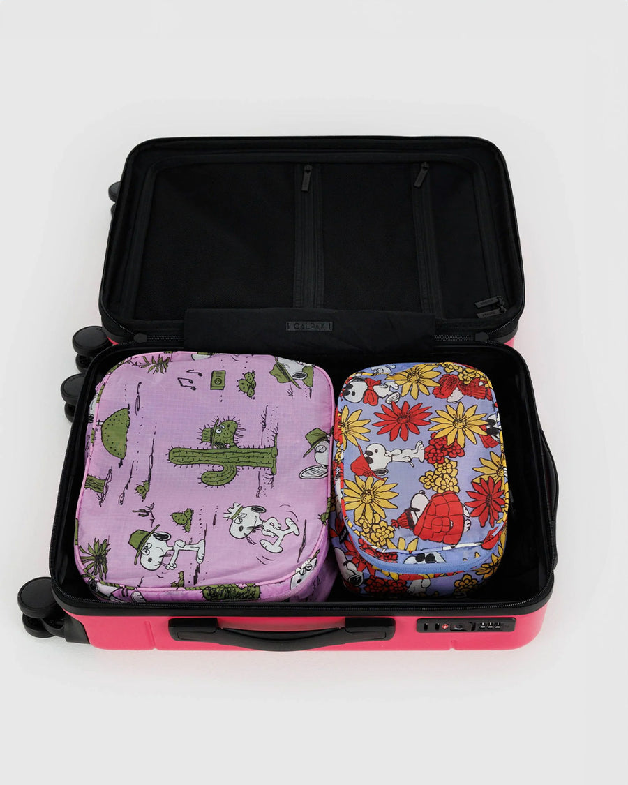 set of two packing cube sets: periwinkle snoopy floral and pink spike desert print in suitcase