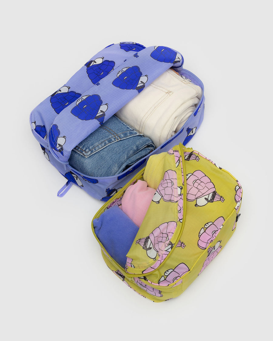 set of 2 packing cubes with yellow with snoopy in a pink puffer coat and blue with snoopy wearing a blue puffer coat with items inside