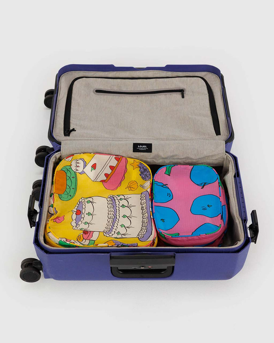 set of two packing set with pink abstract fruit print and yellow abstract pastries print in a suitcase